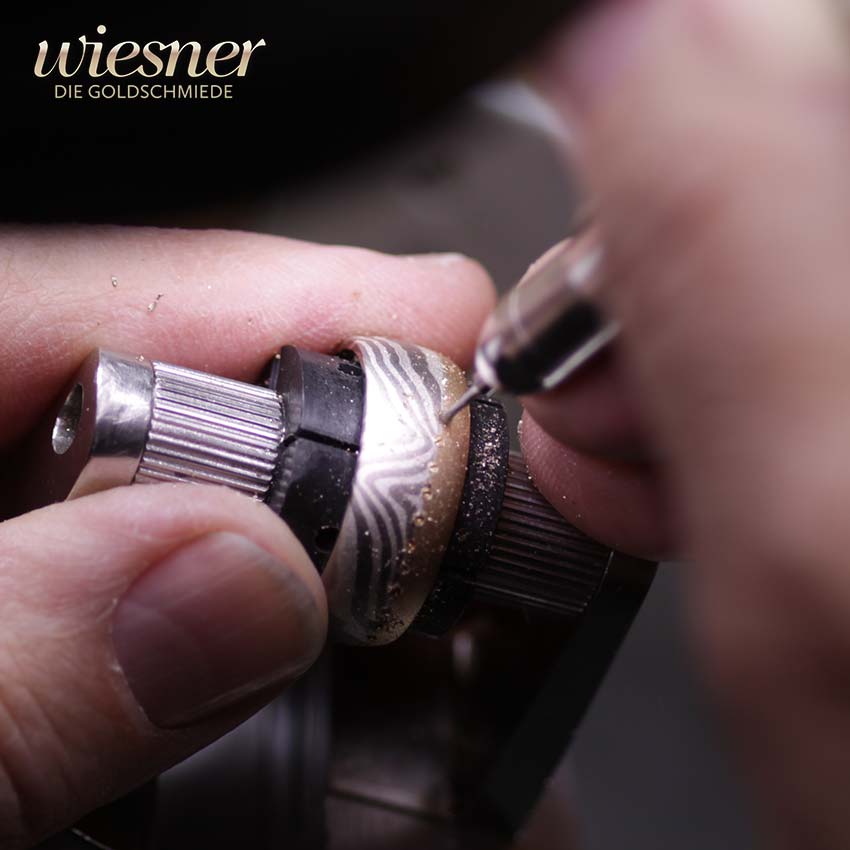 Juwelenfasser bearbeitet die Diamantlinie eines Movingu Mokume Gane Ringes